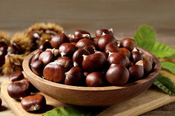 Fresh sweet edible chestnuts on wooden board, closeup