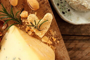 Heart-shaped goat cheese with other types of cheese on a wooden surface.