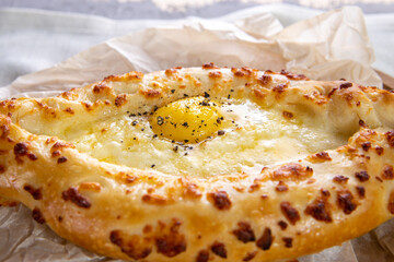 Khachapuri freshly cooked with egg on a wooden tray close up