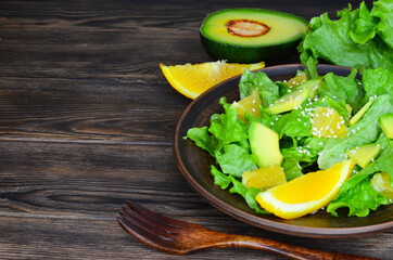 fresh summer homemade salad of vegetables and fruits, orange, lettuce, avocado and sesame seeds, healthy food, organic, vegetarian eco health and immunity products