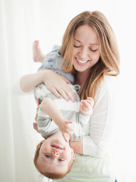 Portrait of young woman embracing baby boy (6-11 months) upside-down