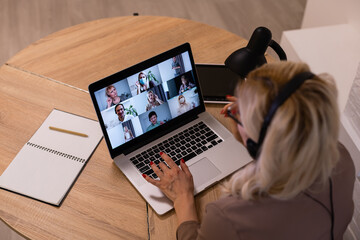 Woman having video chat with colleagues at laptop in office, closeup