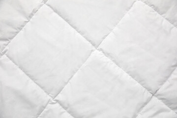 Soft quilted blanket as background, top view