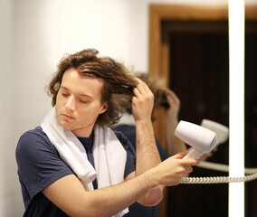 man in the bathroom drying his hair with a hairdryer