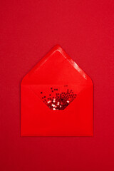 Red star shaped confetti pouring out of red envelope on red background. Flatlay style. Holiday or correspondence concept. Place for text.