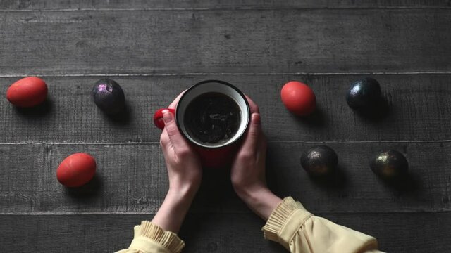 Female hands hold coffee near eggs on a wooden table
