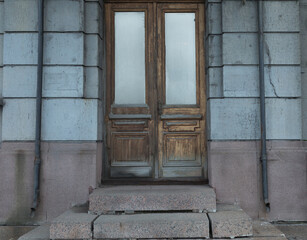 Old vintage brown wood door. Abstract concrete wall exterior and interior around the entrance. Doors of city houses.