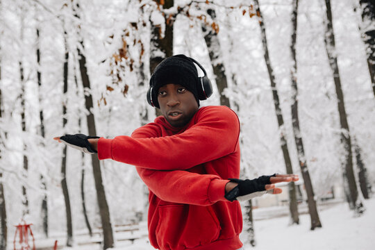 Young African American Man Doing Warm Up Exercise On Winter Day In Forest