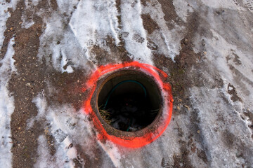 an old sewer pit without a lid surrounded by a red stripe