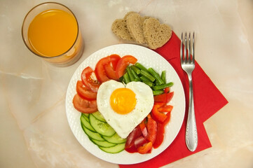 healthy breakfast with egg, bread, tomatoes, cucumber slice, bell pepper, green beans and a glass of juice for Valentine's day morning 