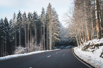 Route déneigée traversant une forêt avec neige pendant hiver 
