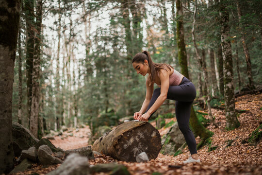 Sports tying shoe lace while standing in forest at Ordesa National Park, Huesca, Spain