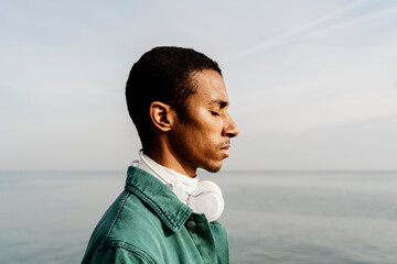 Man with eyes closed day dreaming by sea