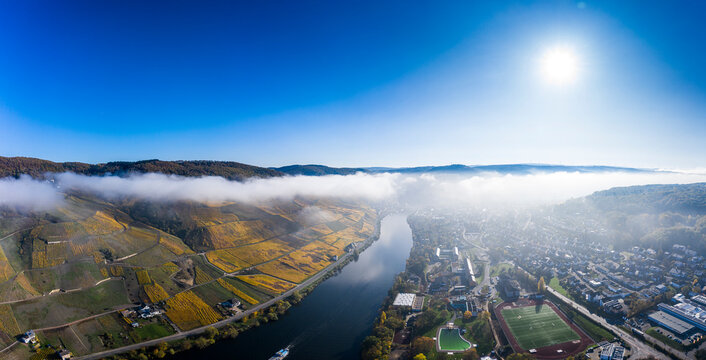 Germany, Rhineland-Palatinate, Bernkastel-Kues, Helicopter view of riverside town and hillside vineyards at foggy autumn morning