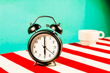 Studio shot of alarm clock standing on white and red striped pattern