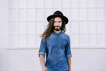 Fashionable young man with cool attitude walking against white wall
