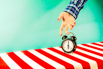 Hand of woman picking up old-fashioned alarm clock