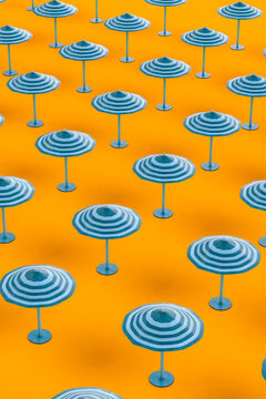 Beach umbrellas arranged in row on orange background