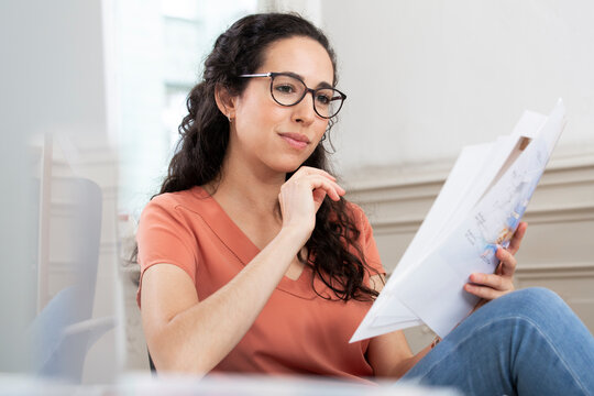 Female professional reading document while sitting in office