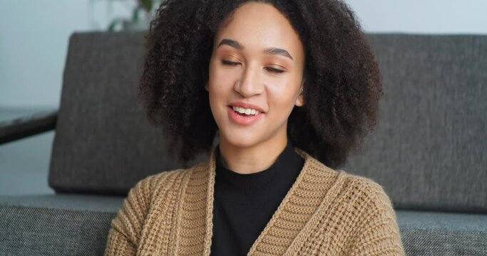 View from webcam Afro American woman speaks in camera answers video call sits at home in living room communicates with teacher to study remotely during coronavirus, student girl shoots video for vlog