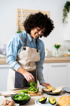 Portrait of young woman preparing vegan sandwiches in kitchen
