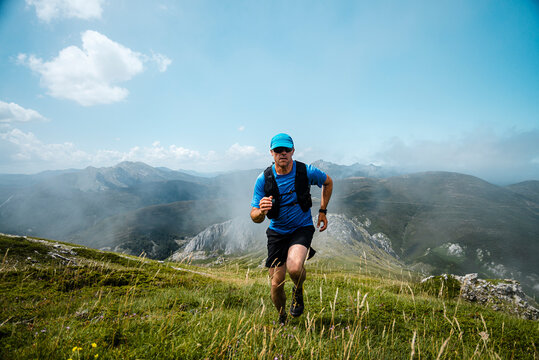 Male athlete running on meadows against sky, Picos De Europa National Park,
 Santa Marina de Valdeon, Castille and Leon, Spain