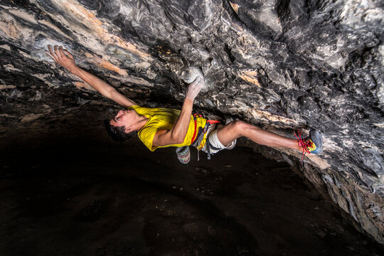 Young sportsman climbing rock in cave