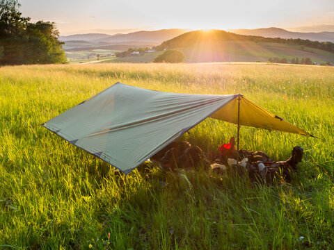 Tarpaulin set in alpine meadow at sunset