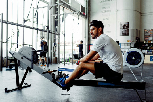 Sportsman looking away while sitting on rowing machine