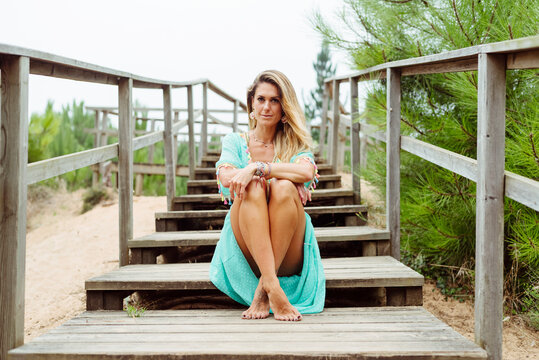 Mid adult woman sitting with legs crossed at ankle on steps at forest