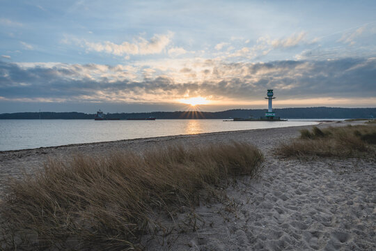 Germany, Schleswig-Holstein, Friedrichsort, Sandy coastal beach at sunrise with lighthouse in background