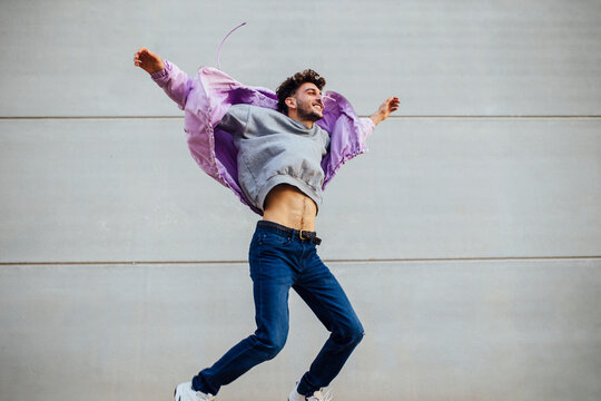 Cheerful man jumping against gray wall