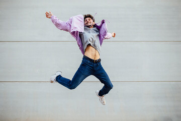 Happy man jumping against gray wall