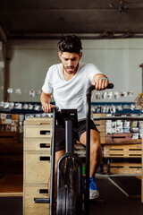 Fototapeta na wymiar Young sportsman exercising on airbike at gym