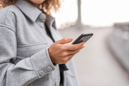 Young woman using smart phone while standing on bridge in city - Powered by Adobe