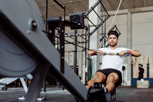 Sportsman exercising with rowing machine at gym