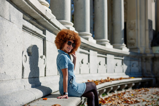Smiling woman with hand in hair at Alfonso Xii Monument, Parque Del Buen Retiro, Spain