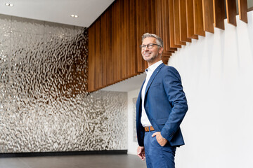 Male entrepreneur with hands in pockets in office lobby