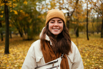 Happy young woman in warm clothing in autumn park
