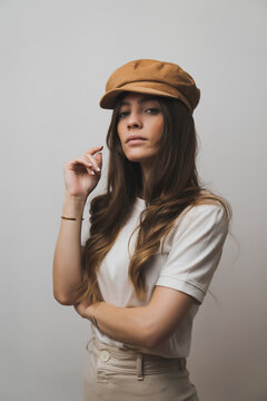 Young beautiful woman wearing cap standing against wall