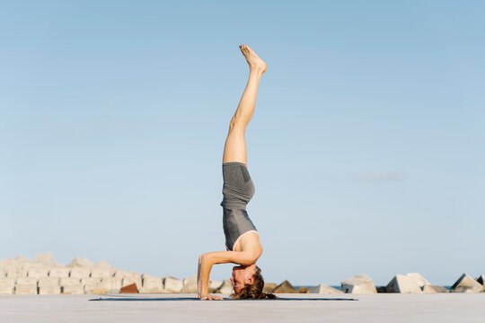 Female sportsperson doing headstand on exercise mat