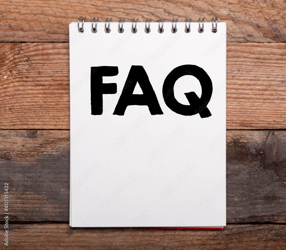 Aufkleber faq text in notebook on wooden table.