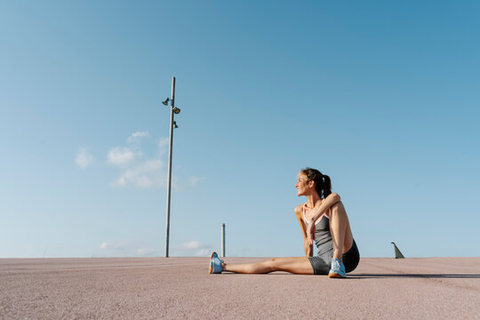 Smiling sportswoman sitting on ground, relaxing on a sunny day