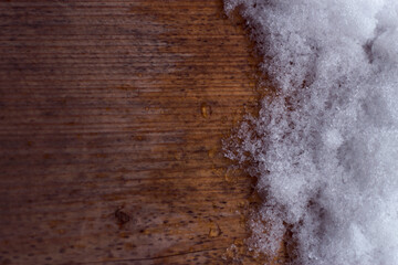 cold melting textured snow on the weathered wooden surface  - winter close up, frozen background