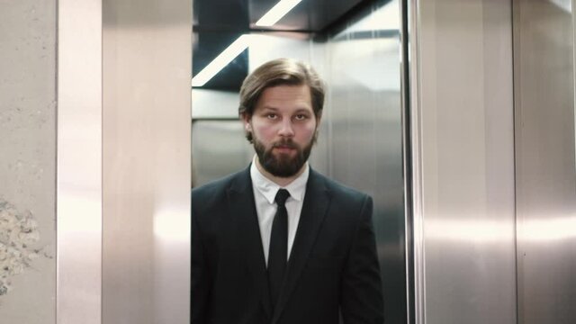 Businessman coming out from elevator in company building.