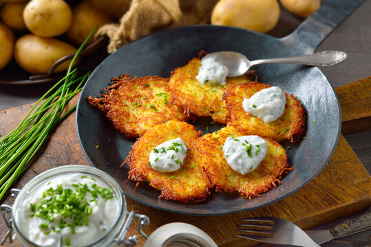 Resche bayerische Kartoffelpuffer mit Schnittlauchquark in der Eisenpfanne serviert &ndash; Crunchy Bavarian potato pancakes with sour cream and fresh chives 