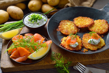 Resche Kartoffelpuffer mit Räucherlachs und Schnittlauchquark in der Eisenpfanne serviert – Crunchy potato pancakes with smoked salmon and chives quark 