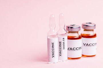 abstract vaccine vials and bottles for injection over pink background. alarm clock near vaccination drugs. vaccination concept