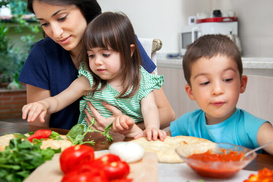 Mother with son and daughter making homemade pizza