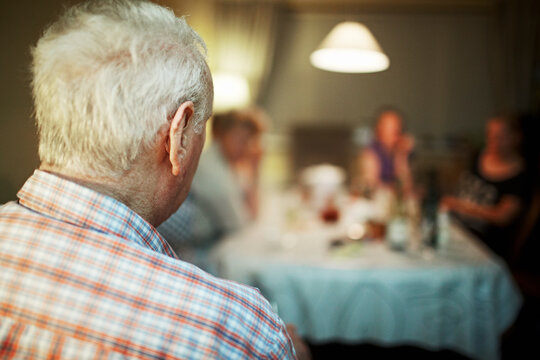 Senior man with grey hair and family in background